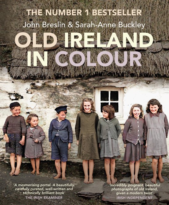 Boekomslag van 'Old Ireland in Colour' met zeven kinderen voor een stenen huisje met rieten dak. De tekst 'OLD IRELAND IN COLOUR' is groot afgebeeld.