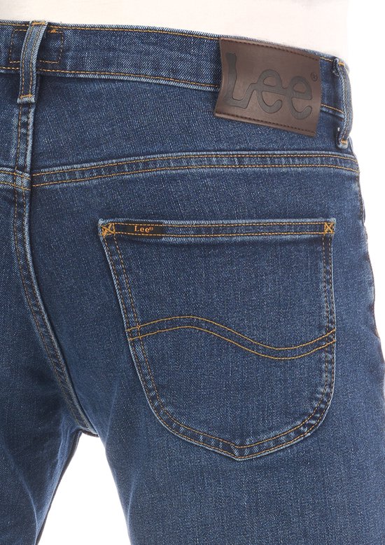 Achterkant van een blauwe jeans met bruin Lee-label op de tailleband en oranje stiksels.