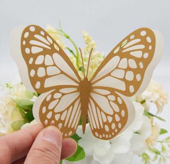 Een hand houdt een bruine papieren vlinder met een open ontwerp vast tegen een achtergrond van bloemen.