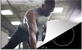 KitchenYeah® Inductie beschermer 76x51.5 cm - Een sterke man tilt tijdens fitness kettlebells omhoog - Kookplaataccessoires - Afdekplaat voor kookplaat - Inductiebeschermer - Inductiemat - Inductieplaat mat