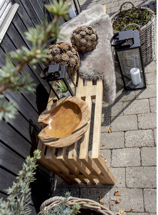 Houten bankje met houten schaal, lantaarns en een schapenvacht.