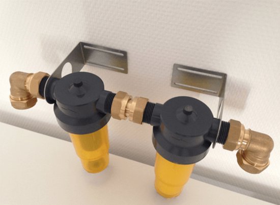 Dubbele waterfilter met gele containers en messing koppelingen, bevestigd aan muurbeugels.