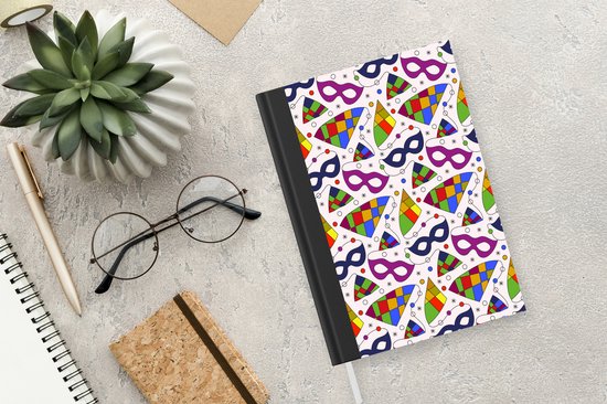 Carnet blanc à motifs de carnaval sur fond marbré, à côté d'une plante et de lunettes.