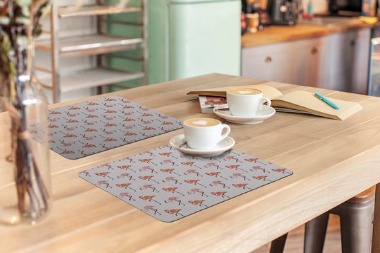 Deux tables avec des sets de table à motifs flamants roses et des tasses à café.