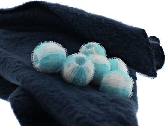 Quatre boules de lavage anti-peluches bleues et blanches sur un tissu bleu foncé.