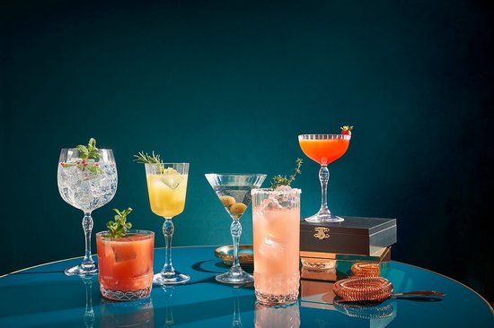 Een verzameling kleurrijke cocktails in verschillende glazen, waaronder een martiniglas met olijven.
