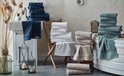 Een badkamer met stapels beige, witte en blauwe handdoeken.