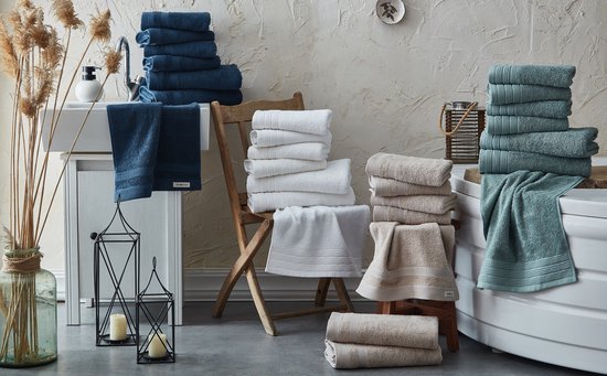 Een badkamer met stapels beige, witte en blauwe handdoeken.