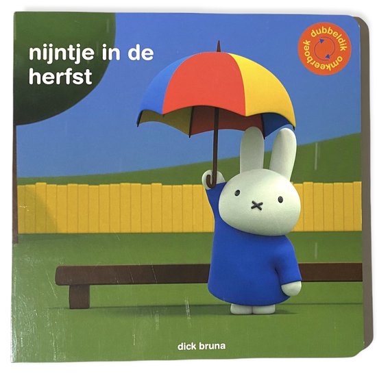 Nijntje met een paraplu in de regen, met een gele schutting op de achtergrond.