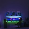 Gaming bureau met drie monitoren, verlicht met gekleurde LED-strips in paars en groen.