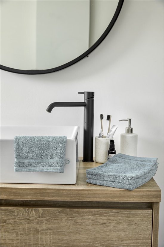 Zeeblauw washandje en stapel handdoeken van Byrklund op een houten badmeubel.