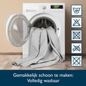 Grijze sprei met ruitpatroon wordt in een wasmachine geplaatst. Volledig wasbaar.