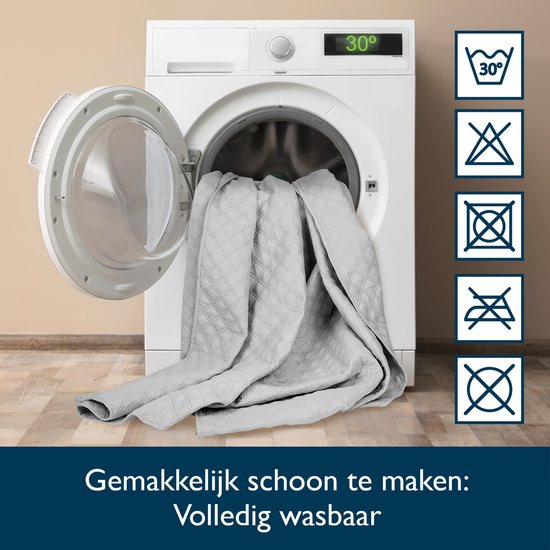 Grijze sprei met ruitpatroon wordt in een wasmachine geplaatst. Volledig wasbaar.