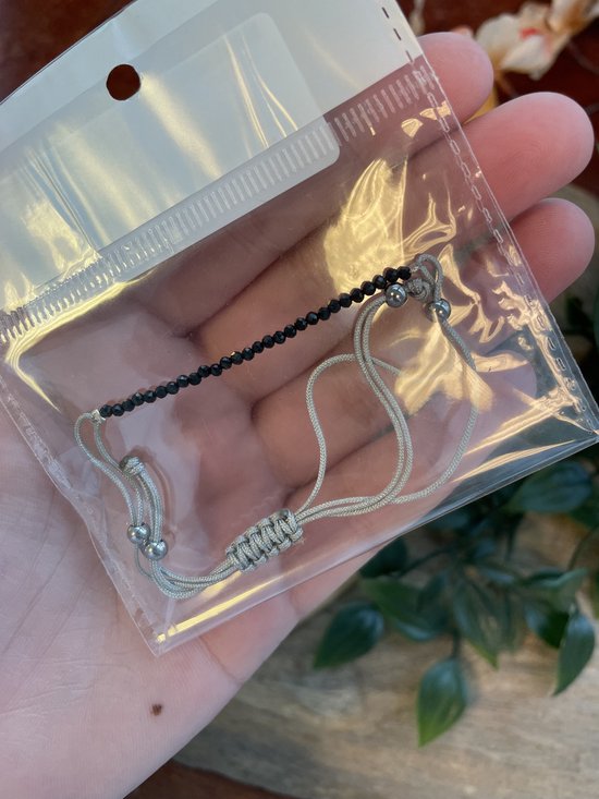 Zwarte facet geslepen kristallen armband met verstelbaar zilverkleurig koord, in verpakking.