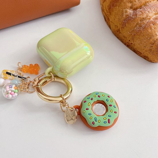 Groene donut sleutelhanger met gekleurde hagelslag en gouden ring, aan een lichtgroene AirPod case.