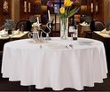 Tafel met wit tafelkleed, gedekte tafel met wijn, glas, kandelaar en bloemen.