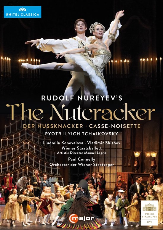 Balletpaar in "De Notenkraker" van Rudolf Nureyev, met een mannelijke danser met witte trui en panty en een vrouwelijke danseres in wit balletpak, met veel kaarsen op de achtergrond.