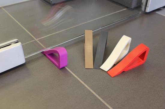 Verschillende deurcdotoren in de kleuren paars, bruin, grijs, wit en rood op een grijze tegelvloer.