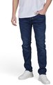 Voorkant van een man met een blauwe, slanke jeans, een witte t-shirt en witte sneakers. De man heeft zijn hand in zijn zak.