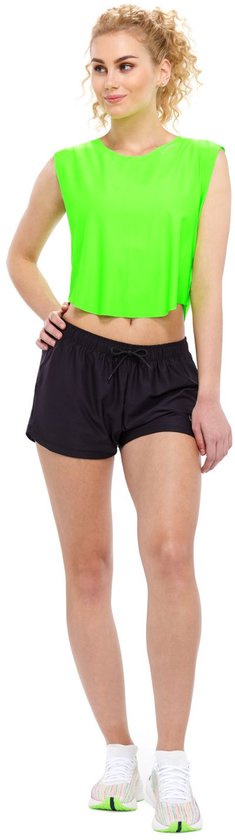 Model met een neon groen cropped top, zwarte shorts en witte sneakers.