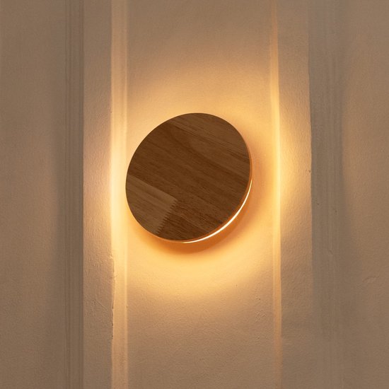 Houten wandlamp met rond, warm licht op een gestructureerde muur.