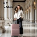 Een roze koffer met een vrouw in een witte coltrui in een hal.