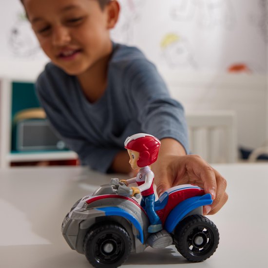 Een jongen duwt de rode, witte en blauwe PAW Patrol ATV van Ryder.