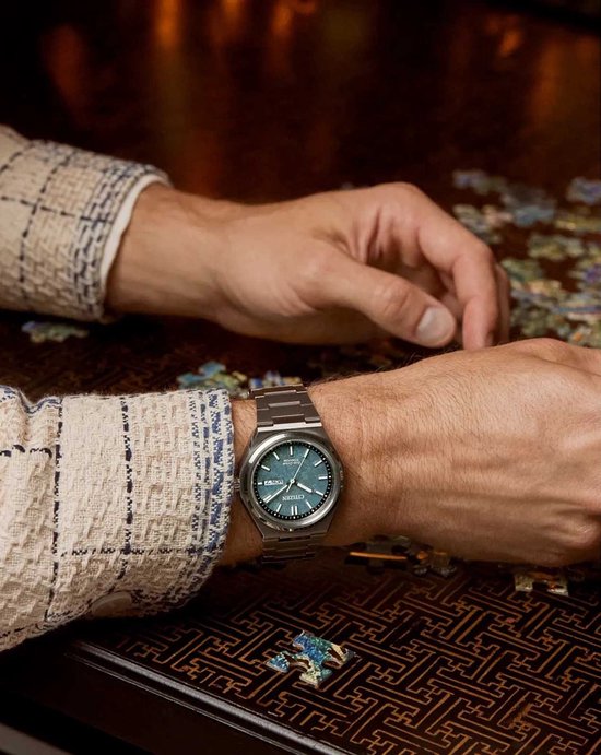 Man met een zilverkleurig Citizen horloge om de pols. Het horloge heeft een blauwgroene wijzerplaat en een titanium band.
