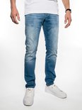 Lichtblauwe jeans met een slim fit pasvorm. Op de achtergrond een witte wand. De broek is voorzien van witte schoenen en een horloge.