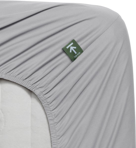 Lichtgrijs hoeslaken met een groen label 'Top side' en elastiek aan de rand.