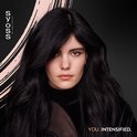Close-up van een model met lang, golvend zwart haar en bruine ogen, met een zachte roze veeg op de achtergrond. Tekst: 'YOU. INTENSIFIED.'