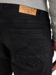 Detail van een zwarte jeans met twee achterzakken, het rechter zakje met sierstiksels.