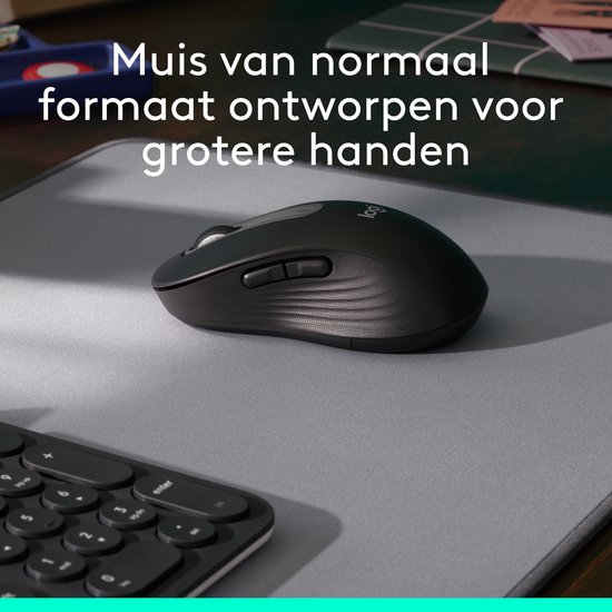 Zwarte muis op een muismat naast een toetsenbord, ontworpen voor grotere handen.
