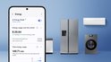 Smartphone met Samsung AI Energy Mode app, toont energieverbruik. Naast een zilverkleurige Amerikaanse koelkast.