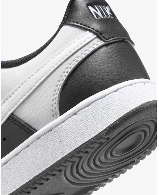 Detail van de hak van een zwarte en witte Nike sneaker. Zwarte 'NIKE' letters op de hak.
