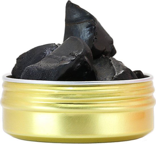 Gouden blik gevuld met ruwe, zwarte shilajit brokjes.
