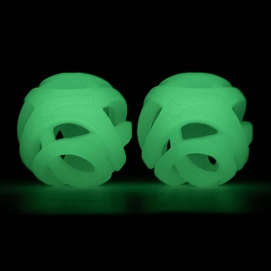 Twee lichtgevende, open gewerkte ballen die groen oplichten in het donker, op een zwarte achtergrond.