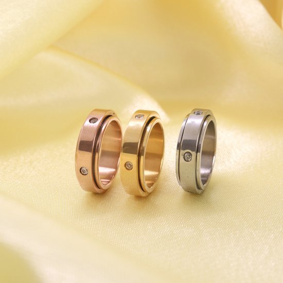 Drie draaibare ringen in rosé goud, goud en zilver, elk met vier kleine steentjes.