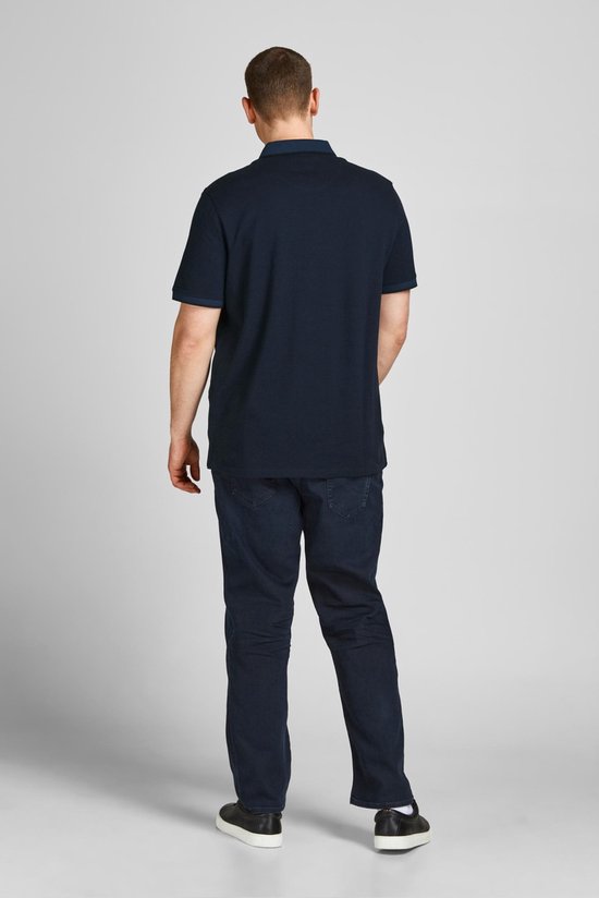 Man van achteren gezien in een donkerblauwe polo en donkere spijkerbroek.