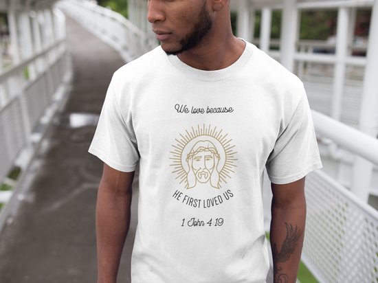 Shirt - We love because he first loved us - Wurban Wear | Grappig shirt | Geloof | Unisex tshirt | Religie | Vloerkleed | Bidden | Bijbel | Christendom | Wit