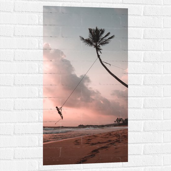 WallClassics - Muursticker - Persoon Slingerend aan Liaan van Palmboom op Onbewoond Eiland - 50x100 cm Foto op Muursticker