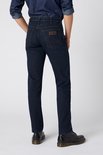 Achteraanzicht van een man in een donkerblauwe Wrangler jeans met bruin leren merklabel op de achterzak.