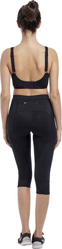 Vue arrière d'une femme portant un soutien-gorge de sport noir à bretelles croisées et un pantalon de sport capri noir.