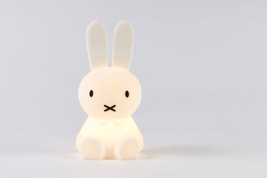 Zittend, verlicht Miffy-lampje met lange oren en kruisjesmondje, op witte achtergrond.