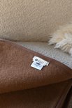 Bruine wollen deken met label "WOLLIES Amsterdam - PURE NEW WOOL PILE".