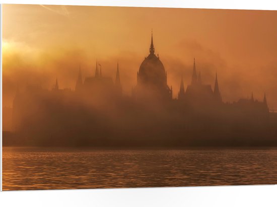 PVC Schuimplaat- Foto van Hongaars Parlementsgebouw aan het Water met Mist Ervoor - 105x70 cm Foto op PVC Schuimplaat