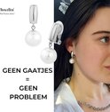Twee zilverkleurige oorclips met witte parels, op de foto een oorclip gedragen door een vrouw. 'GEEN GAATJES = GEEN PROBLEEM'.