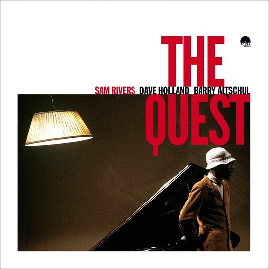 Albumhoes met de titel 'The Quest' in rode letters. Een man met een witte hoed en jas staat naast een vleugel.