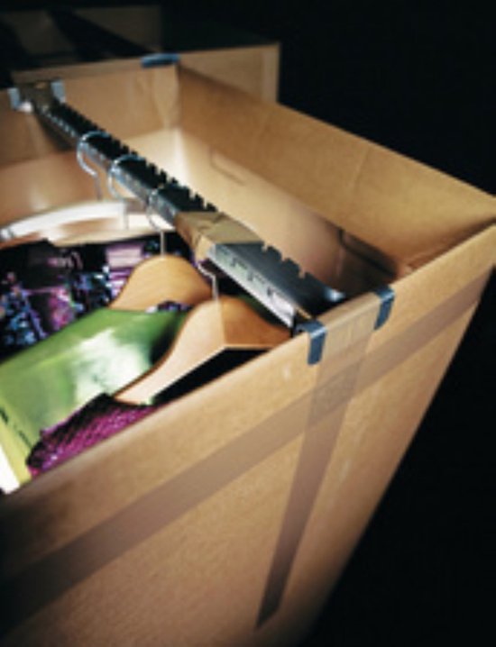 Een open verhuisdoos gevuld met kleding op hangers.