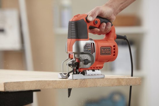 Oranje en zilveren Black+Decker decoupeerzaag die in een stuk hout zaagt.